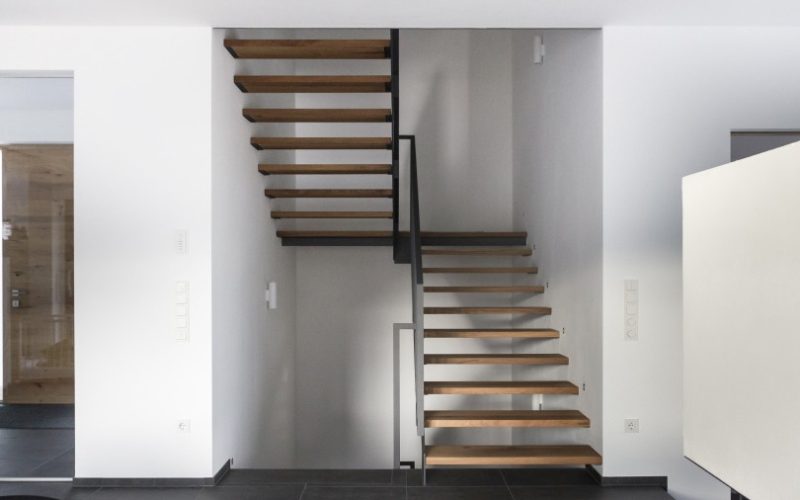 Eine schlicht-moderne freitragende Treppe mit Holzstufen gibt einem Wohnraum ein luftiges Ambiente.